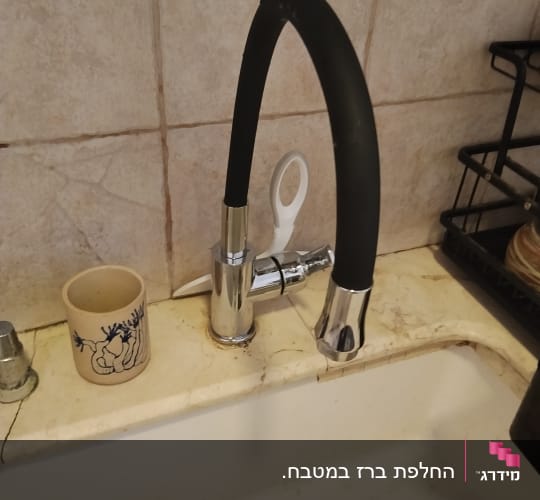 ברז מטבח נשלף בעל פיה גמישה שחורה מותקן על משטח שיש